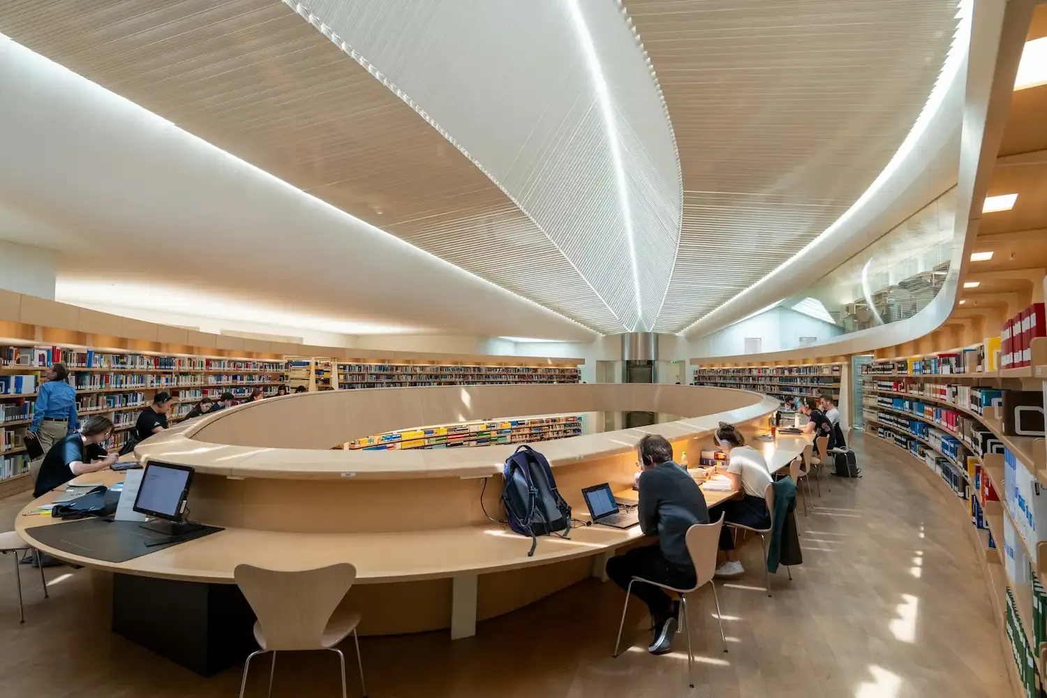 Innenansicht einer modernen Bibliothek mit arbeitenden Menschen.